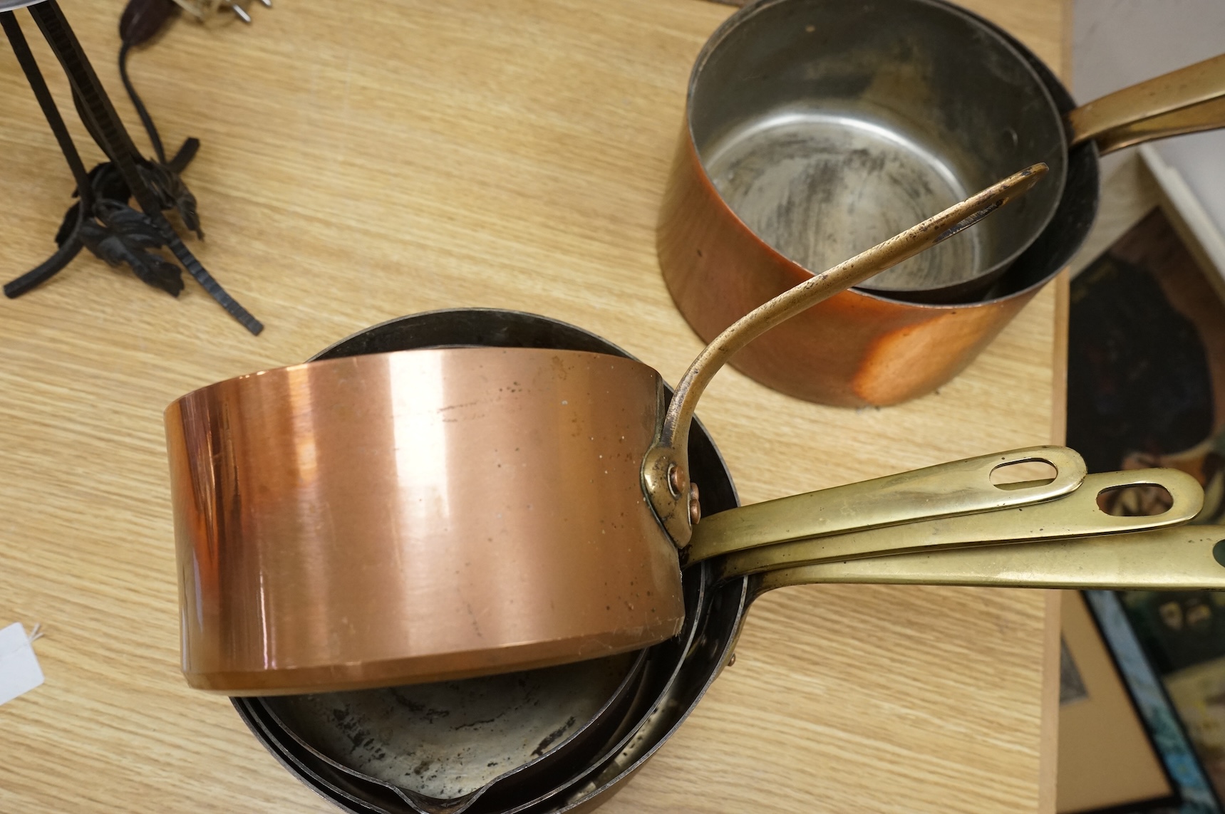 A set of three graduated copper and brass handled Saucepans and a similar set with pouring lid, largest 40cm in length